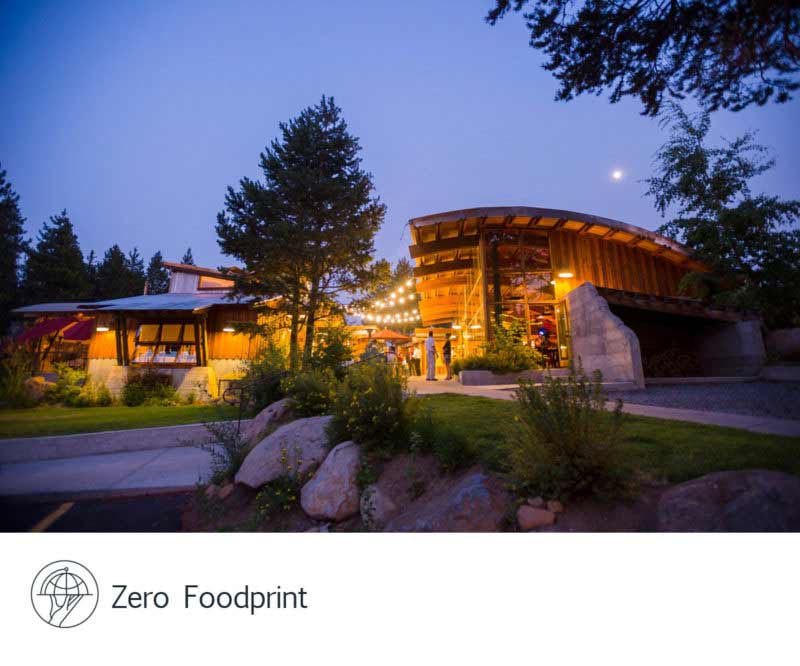 Stella Restaurant exterior illuminated at dusk with the Zero Foodprint logo.